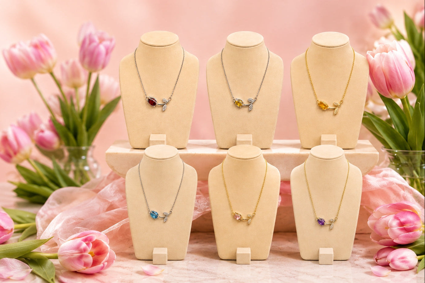 Necklaces on mannequin heads with pink tulips in the background